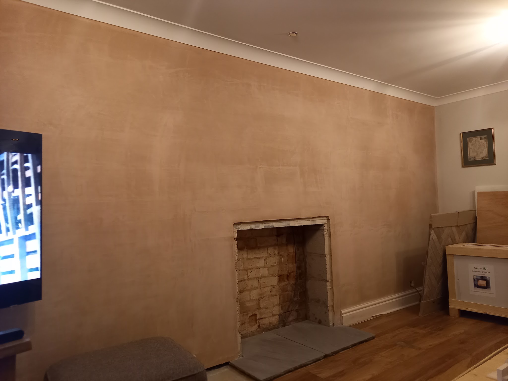 A living-room wall freshly skimmed around an open fireplace